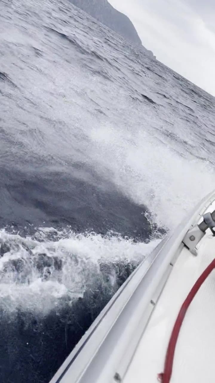 The bow cutting through big waves, spray flying along the hull
