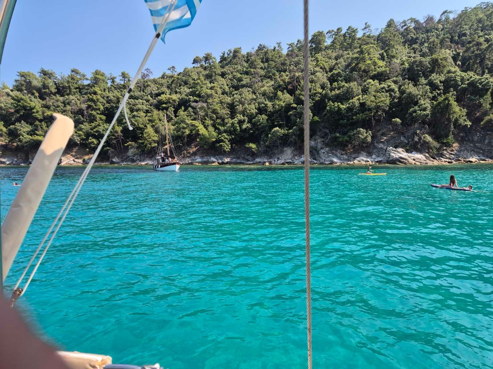 Turquoise water below pine covered hills, seen from the deck
