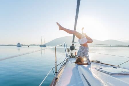 A woman in a yoga headstand on the deck of a yacht at anchor